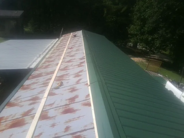 Old rusted panels beside newly installed green metal roofing — Wind Damage Roof Repair by Roofing Brothers in Edisto Island