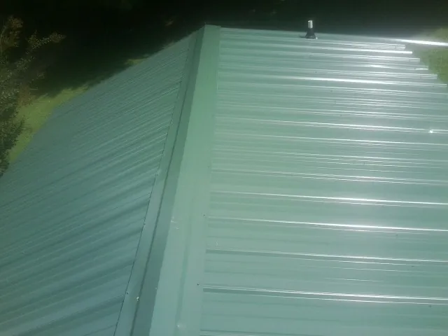 New green metal panels meeting at the ridge of a roof — Flat Roof Repair work by our crew in Edisto Island