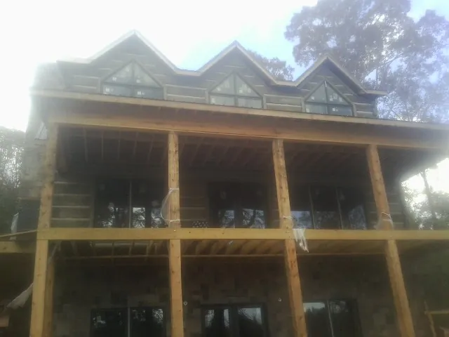 Dormers and porch framing on a large log home under construction — Roof Coating work by our crew in Edisto Island