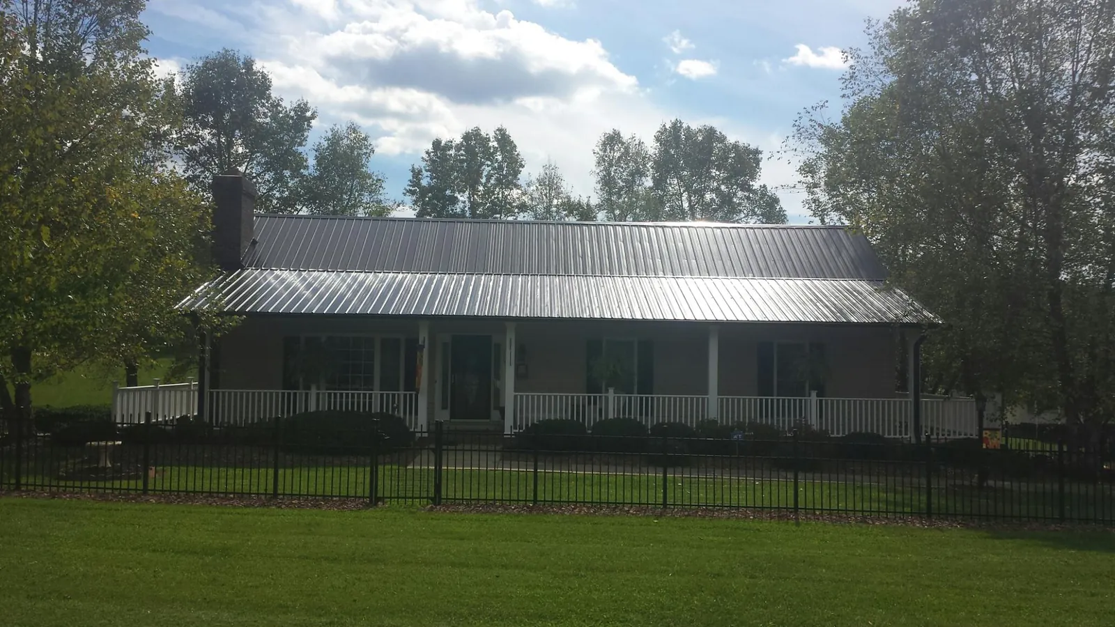 Gray metal roof on a brick ranch with a full width front porch — Gutter Guard Installation work by our crew in Edisto Island