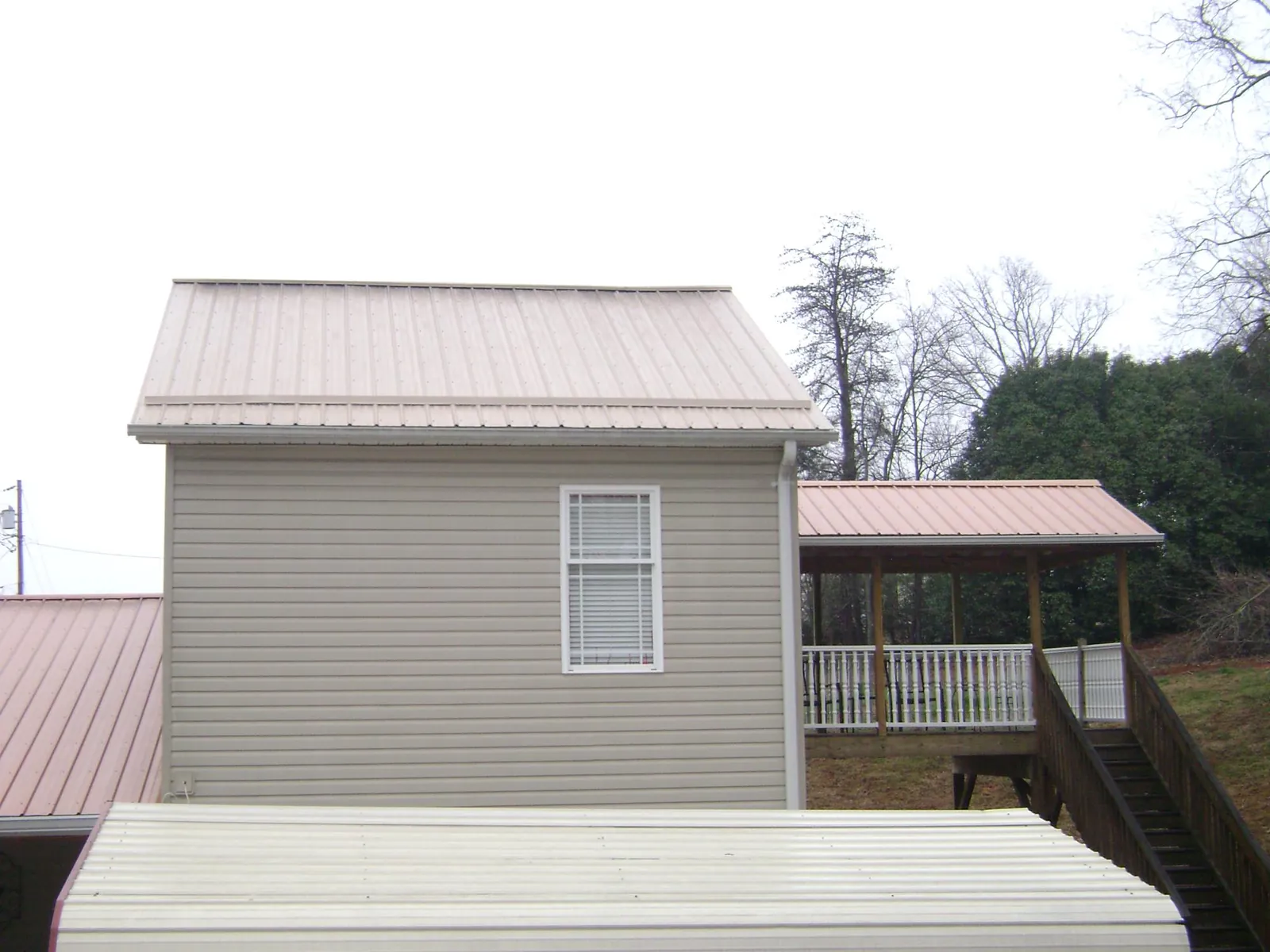 Tan metal roofs on a two story addition and attached porch, from a Roof Replacement job in Edisto Island