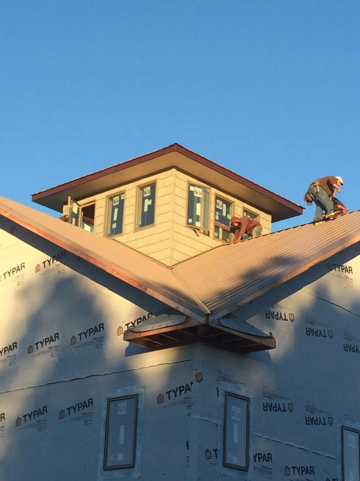 Roofers working around a rooftop cupola on a new metal roof at sunset — Roof Waterproofing in Edisto Island by Roofing Brothers